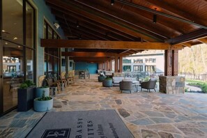 An outdoor patio area with stone flooring, wooden beams, and seating arrangements. - Embassy Suites by Hilton Gatlinburg Resort (GATLINBURG)