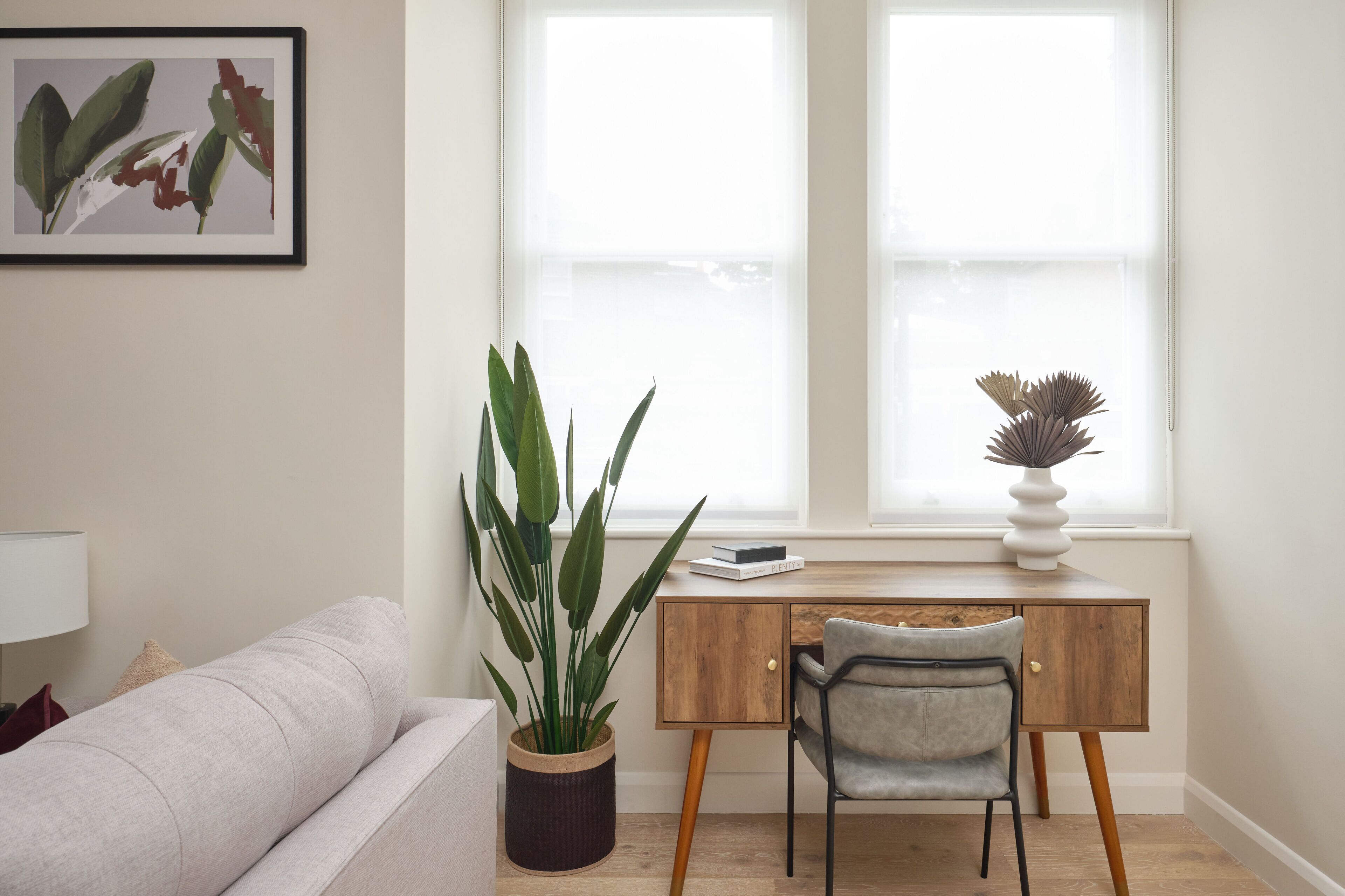 A modern office space with a desk, chair, and potted plants.