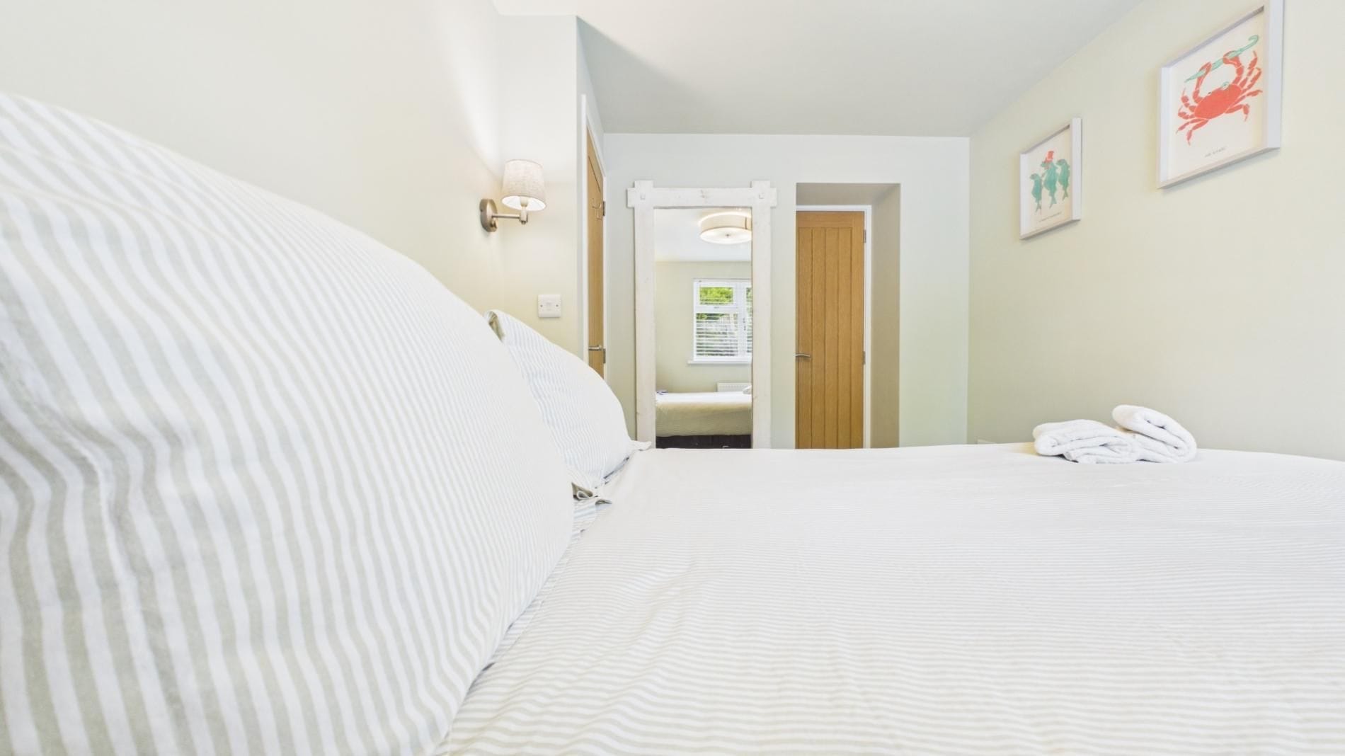 Une chambre d’hôtel avec un lit, une porte donnant sur une salle de bain et une serviette sur le lit.