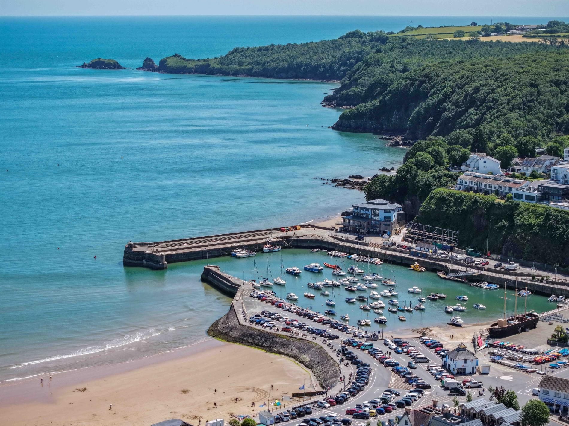 Une ville côtière dotée d’un port de plaisance, d’une plage de sable et d’immeubles résidentiels.