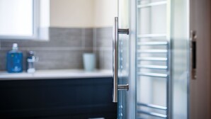 Una cucina moderna con una porta in vetro, una maniglia in acciaio inox e un piano di lavoro con una bottiglia blu e un contenitore bianco.