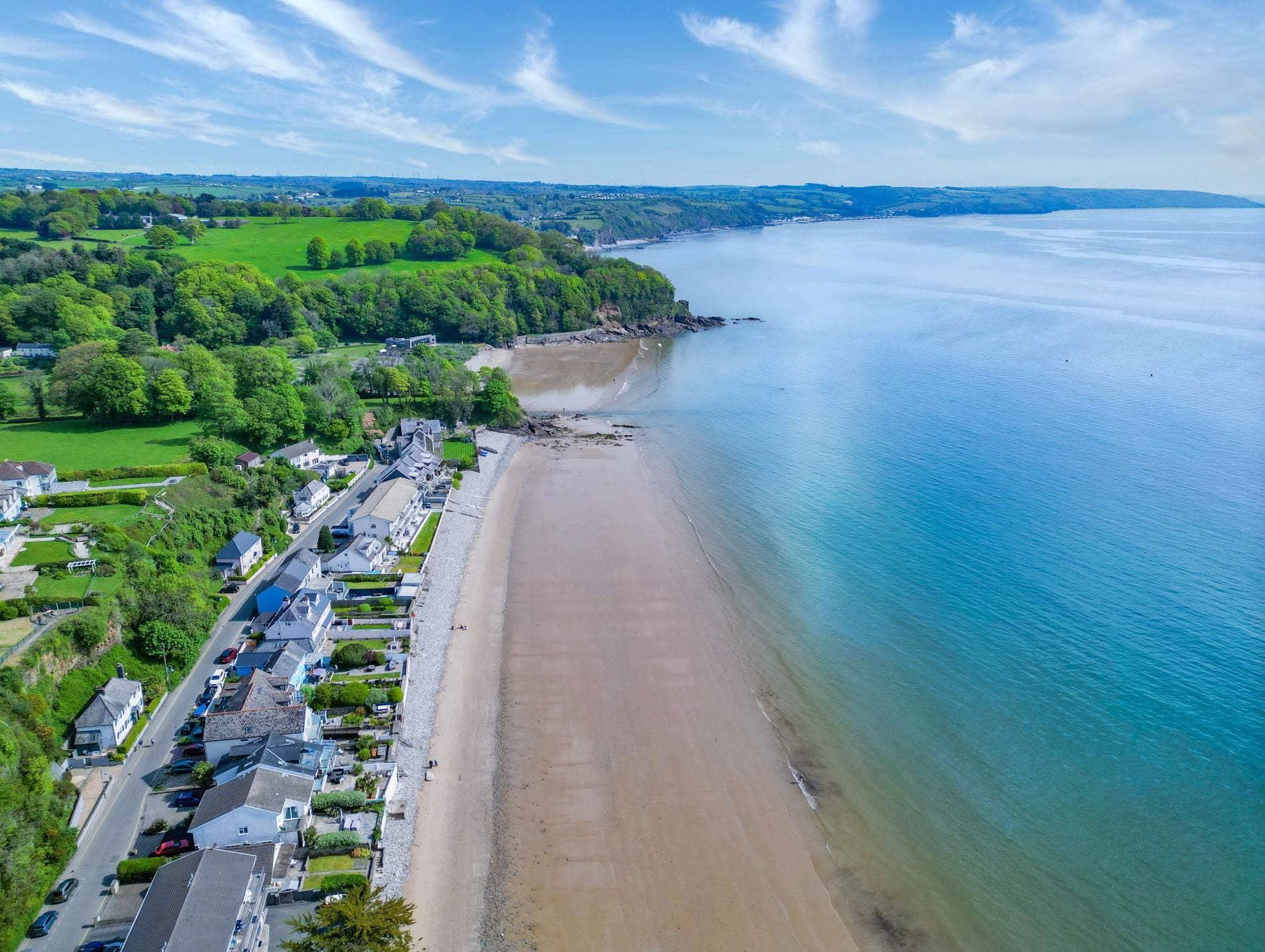 Uma cidade costeira com uma praia de areia, edifícios residenciais e vista clara para o mar.