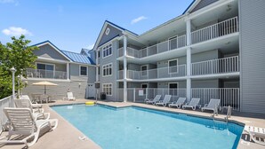A multi-story hotel with a swimming pool, outdoor seating, and a covered area.