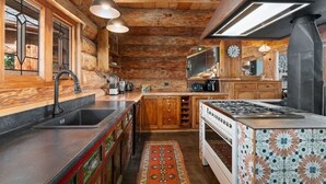 Eine rustikale Küche mit Holzwänden, einem eingebauten Herd und einem großen Fenster.