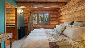 Ein Schlafzimmer in einer Blockhütte mit einem Bett, einem Tisch und einem Fenster mit Vorhängen.