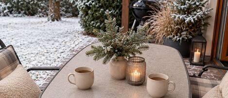 A cozy outdoor seating area with a table, chairs, and a potted plant.
