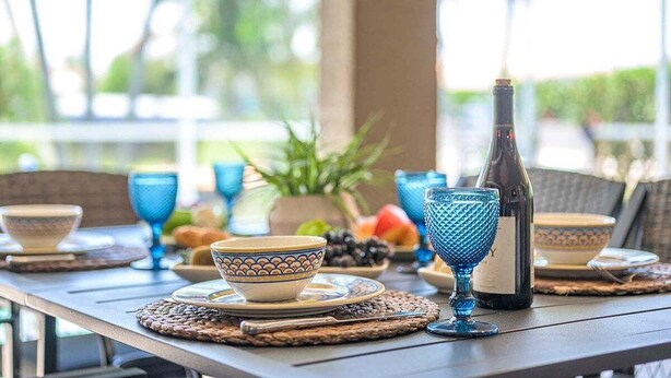 A table set with blue glassware, a bottle, and plates with bowls. - Feeling TipSea | Heated Pool | Gulf Access & Dock (Cape Coral)