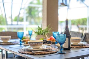 A table set with blue glassware, a bottle, and plates with bowls. - Feeling TipSea | Heated Pool | Gulf Access & Dock (Cape Coral)