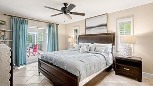 A bedroom with a large bed, a ceiling fan, a nightstand, and a view of the outdoors. - Feeling TipSea | Heated Pool | Gulf Access & Dock (Cape Coral)