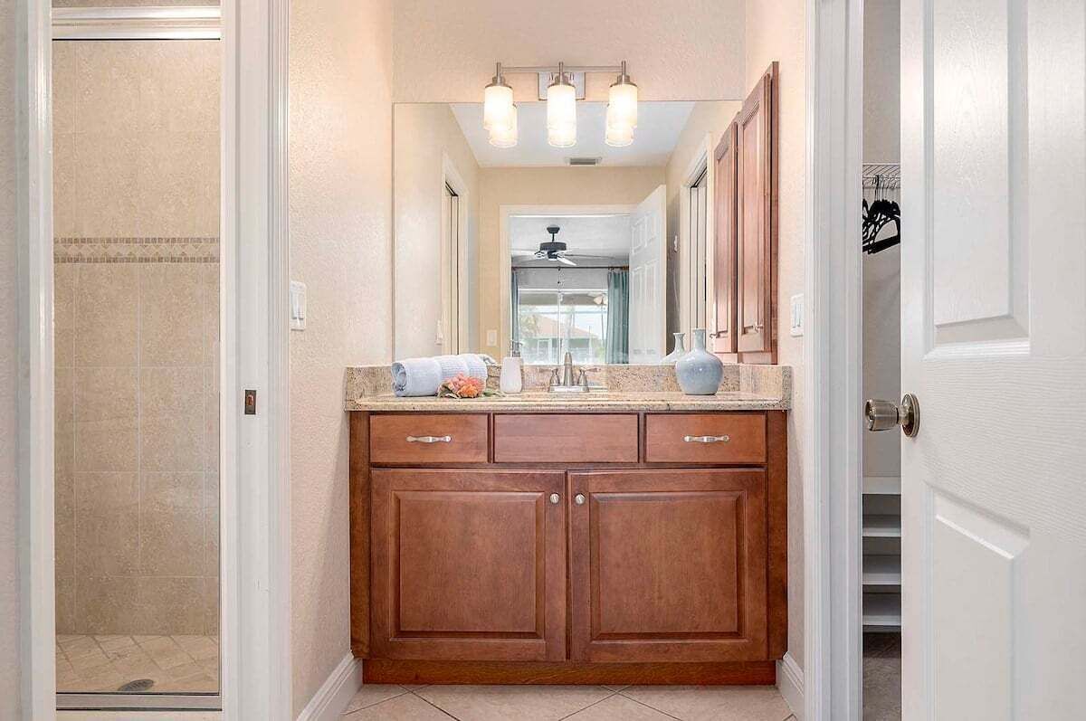 A bathroom with a wooden vanity, a shower, and a ceiling light fixture.