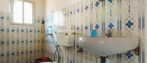 A bathroom with a toilet, sink, and window.