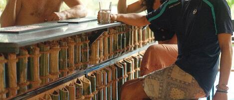 Un área de bar con paredes de bambú, una barra y taburetes.