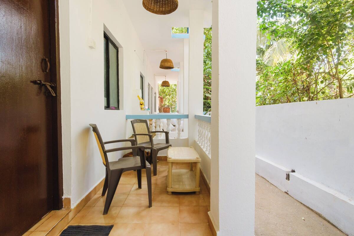 Un pasillo con sillas y una pequeña mesa, que conduce a un balcón con vistas a la vegetación.
