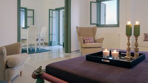 Une pièce avec un lit, une chaise, une table avec des bougies et une vue sur l’extérieur.