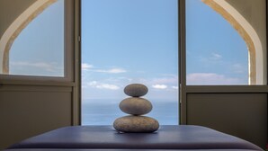 Une vue à travers une fenêtre en arc, avec une pile de pierres posée sur une table.
