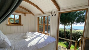 A bedroom with a bed, a window, and a view of the outdoors.