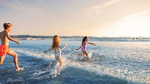 Three people playing in the water at a beach.