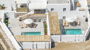 Vista aérea de un moderno resort con varias piscinas, tumbonas y un área de estar cubierta.