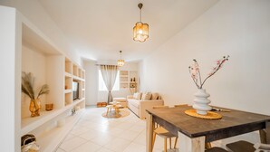 Una sala de estar moderna con comedor, paredes blancas y un sofá.