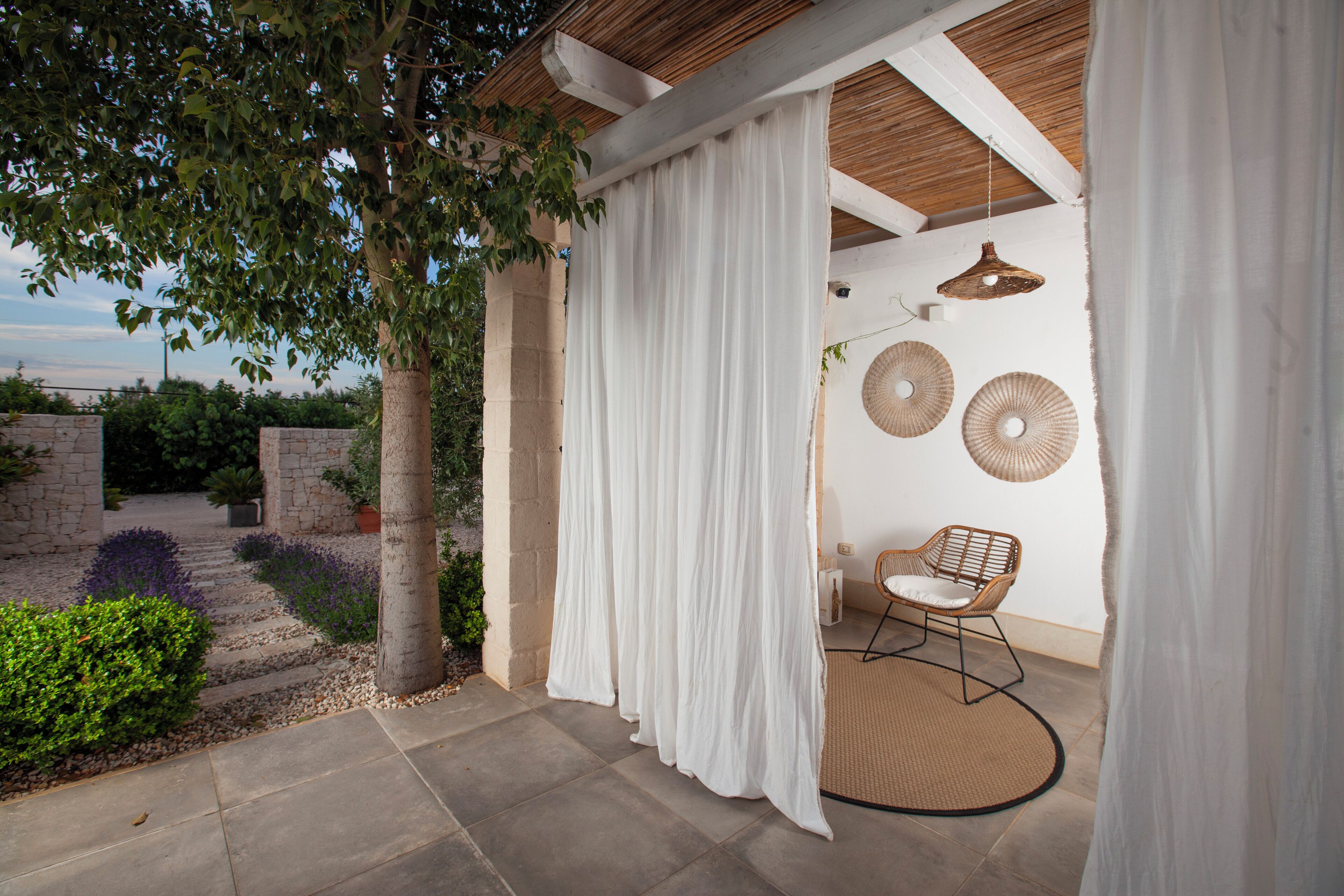 Un espacio al aire libre techado con una silla de mimbre y decoración mural tejida.
