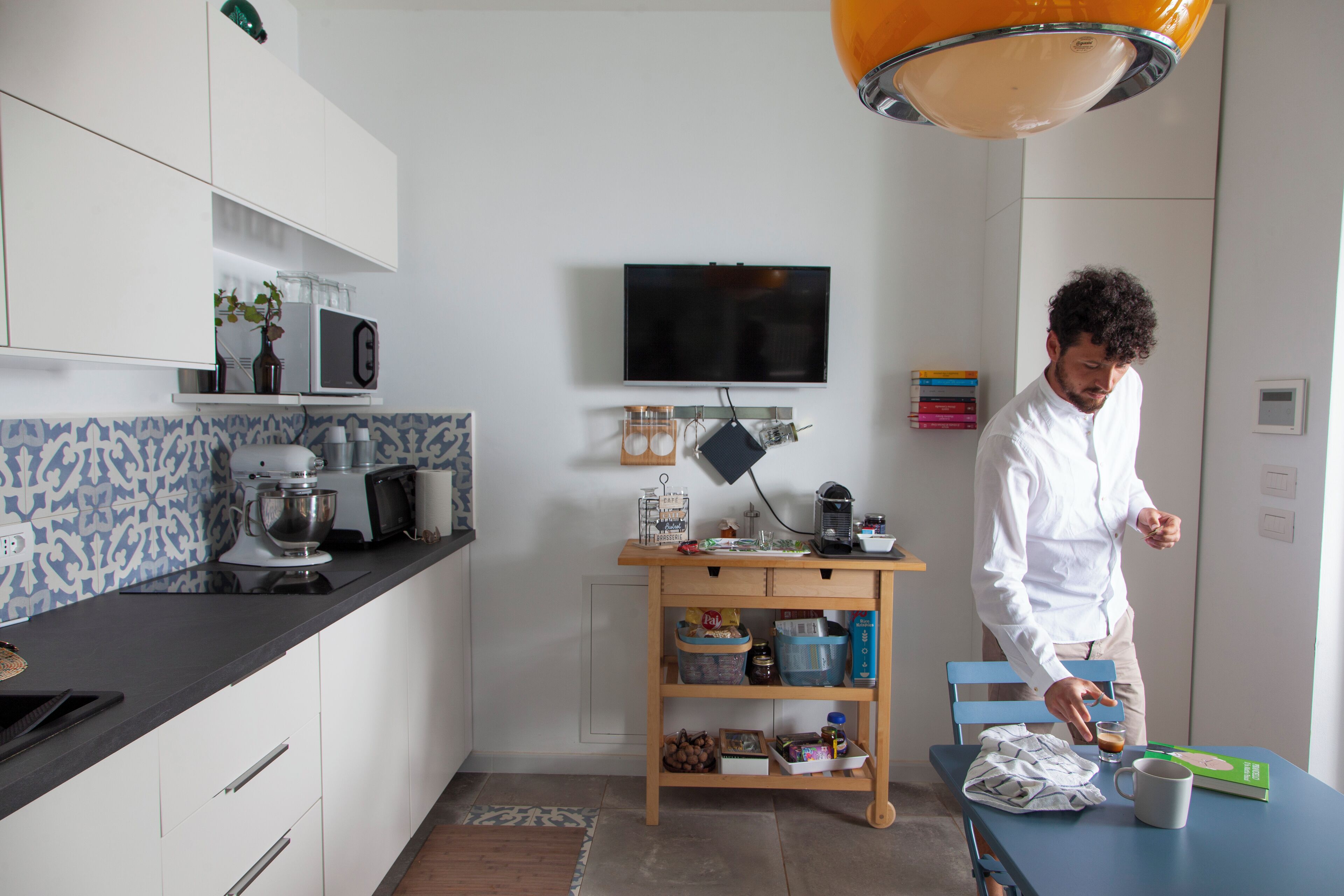 Una cocina moderna con armarios blancos, encimera negra y mesa de madera.