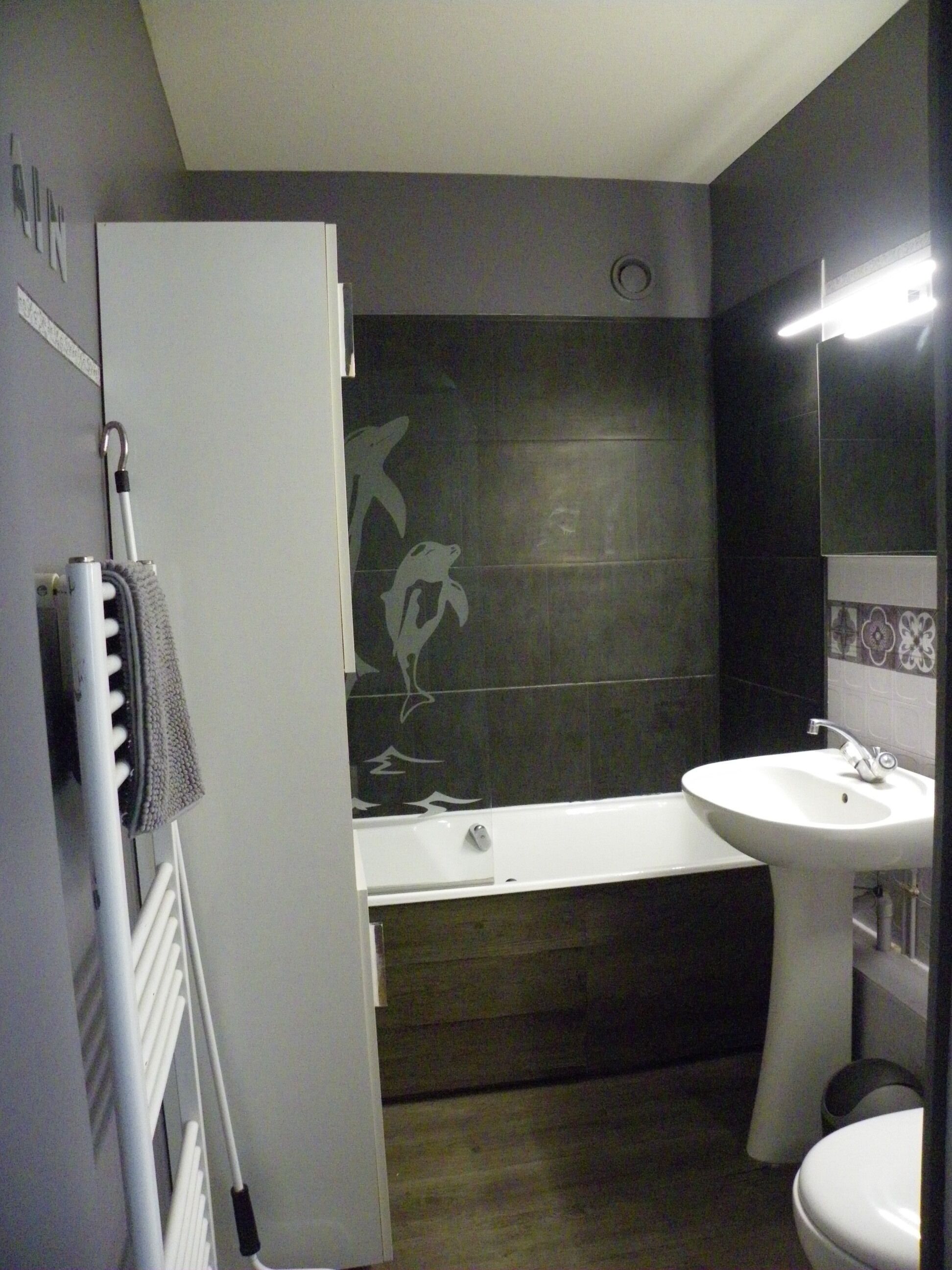 A bathroom with a bathtub, a sink, and a towel rack.