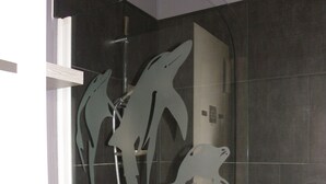 Une douche avec des motifs de dauphins découpés dans la porte en verre.