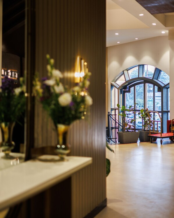 A modern interior with a reception desk, a large arched window, and a plant arrangement.