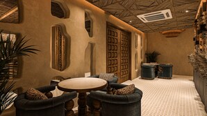 Un rincón tranquilo con una mesa redonda, asientos cómodos y un panel decorativo en la pared.