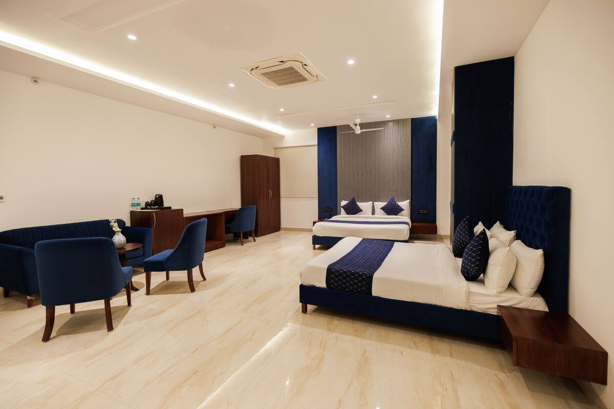 Quarto de hotel moderno com uma cama grande, uma escrivaninha, um sofá e uma poltrona.