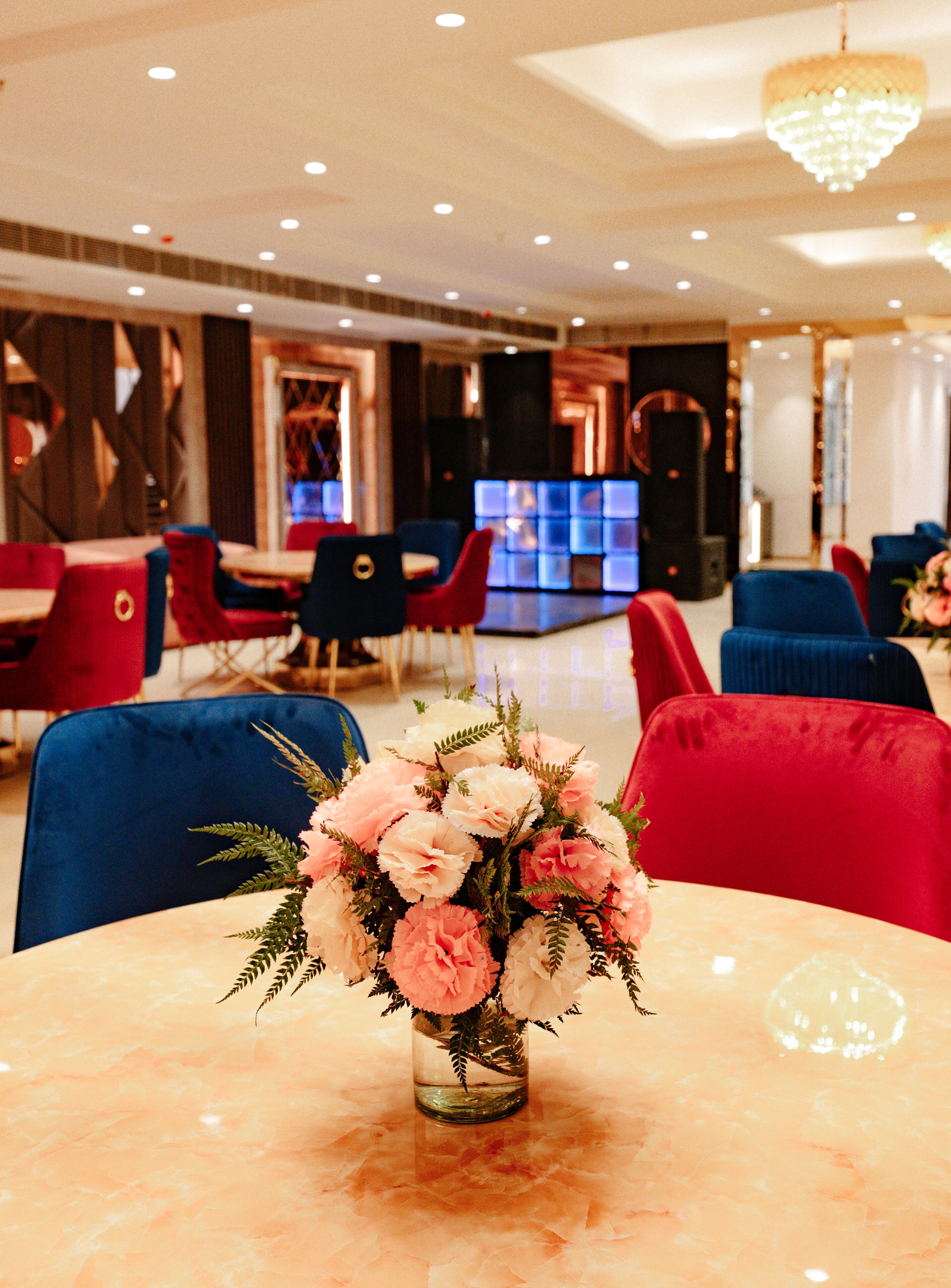 Eine Hotelhalle mit einer Marmorrezeption, roten und blauen Sitzgelegenheiten und einer Chandelüster.