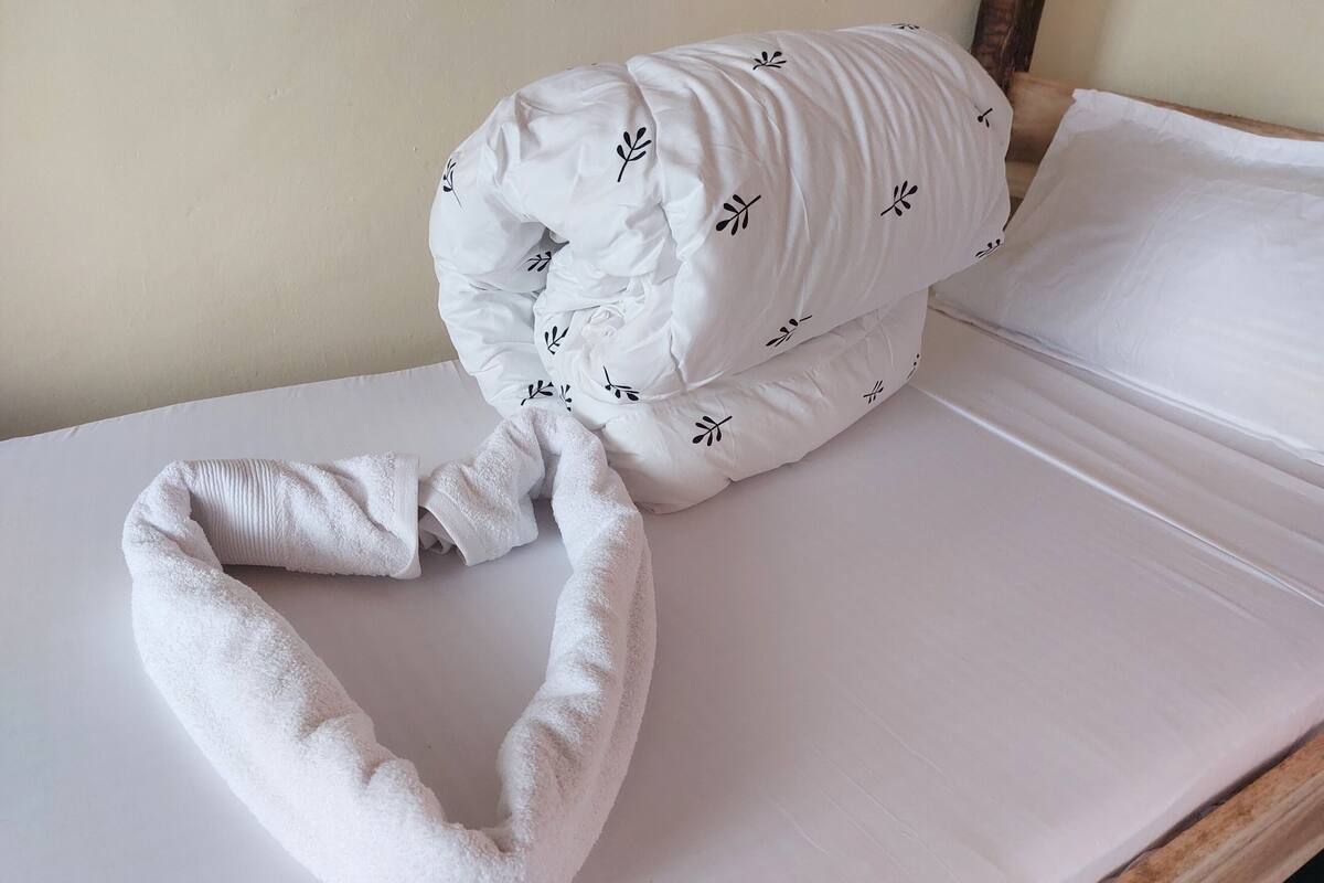 Una cama bien hecha con una almohada y una toalla blancos.