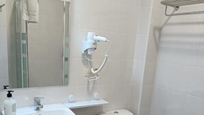 A bathroom with a white sink, a toilet, and a shower area. - Albergue Miraiso (Arzua)