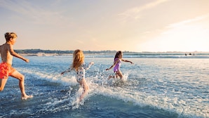 Tres personas jugando en el agua en la playa.