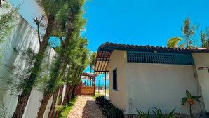 A pathway leading to a building with a tiled roof, surrounded by trees and a grassy area. - Pousada Mar a Vista (Ipojuca)