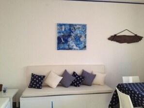 Et værelse med en seng, et lille bord og et billede på væggen.
