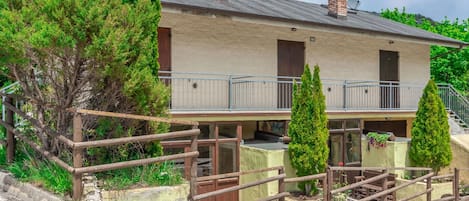 A two-story building with a balcony, a wooden fence, and a gravel driveway.