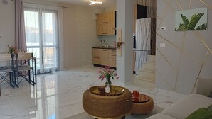 Un salon moderne comprenant un coin repas, une cuisine et un escalier.