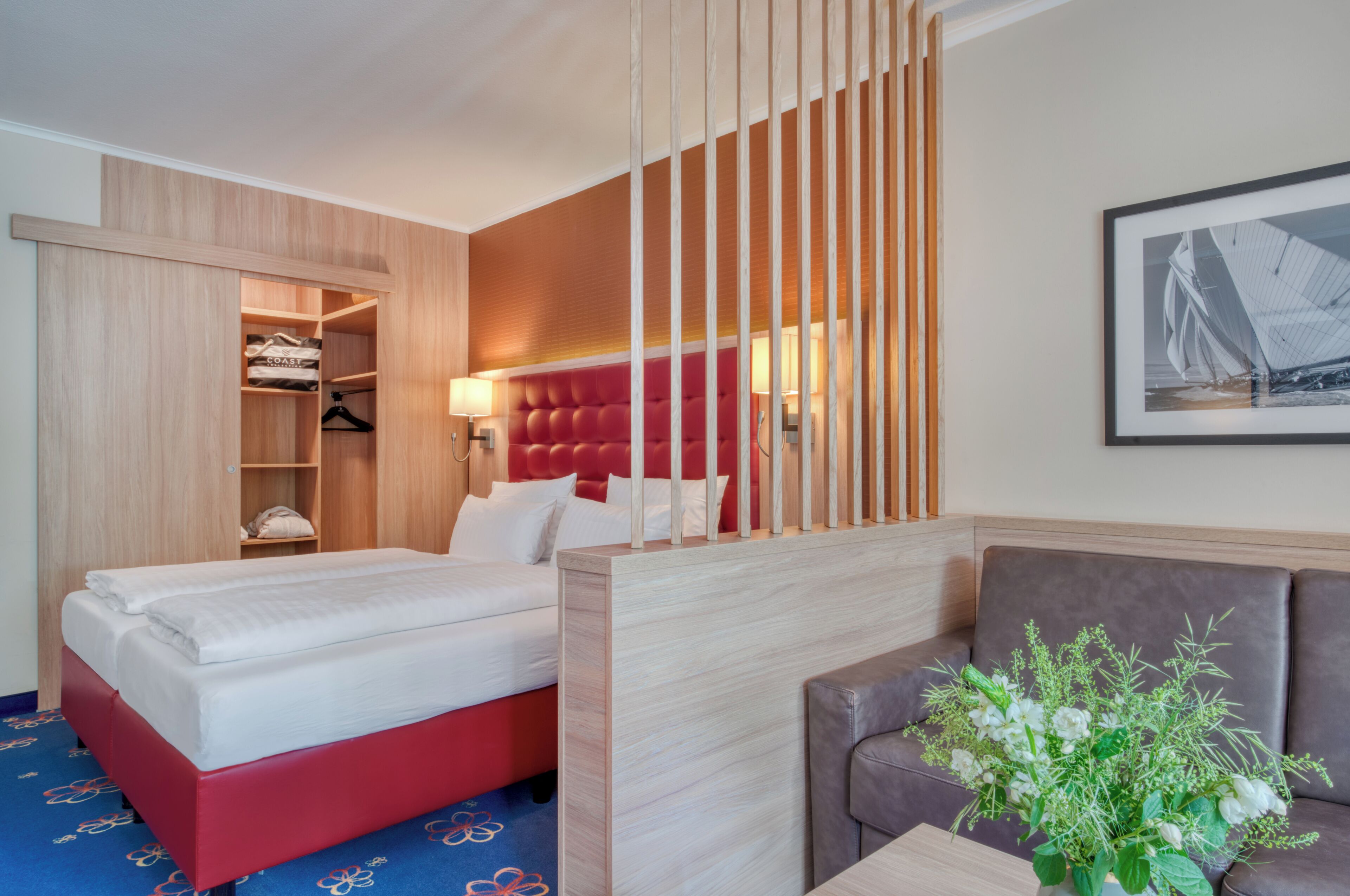 Ein Hotelzimmer mit einem Bett, einer Sitzecke, einem Kleiderschrank und einer Wandlampe.