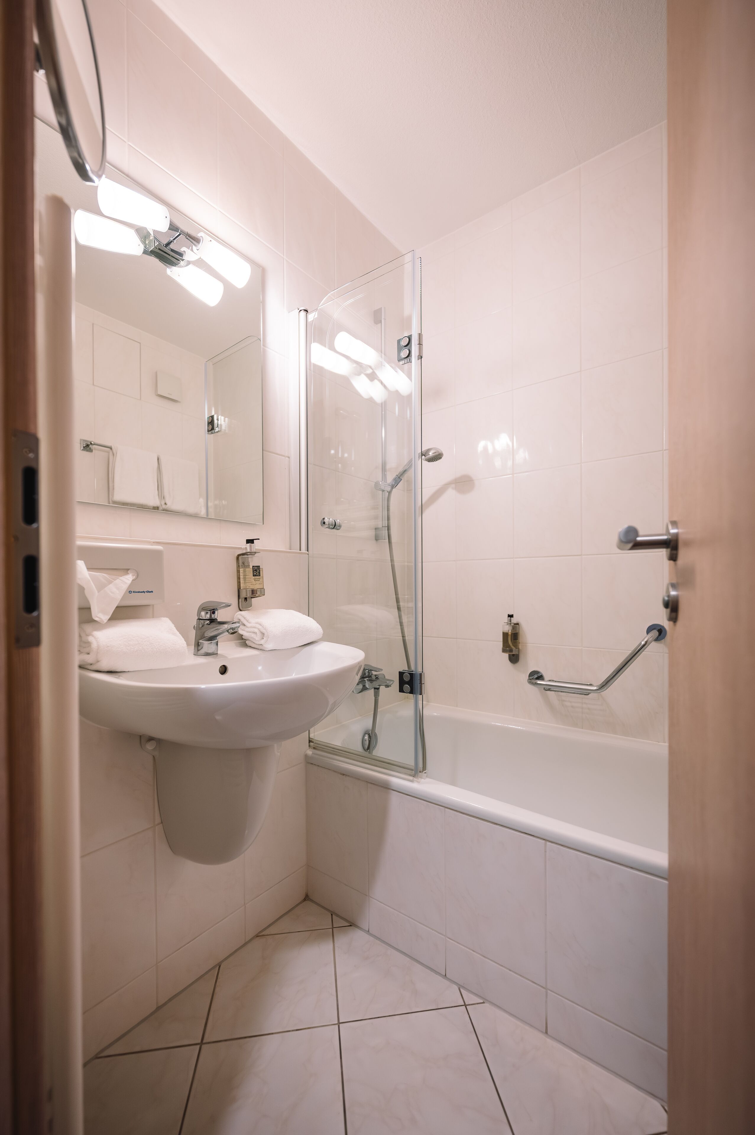 Un baño moderno con ducha de vidrio, un lavamanos con espejo y una bañera.
