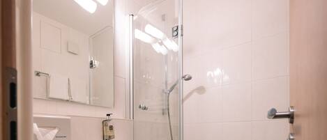Un baño moderno con ducha de vidrio, un lavamanos con espejo y una bañera.