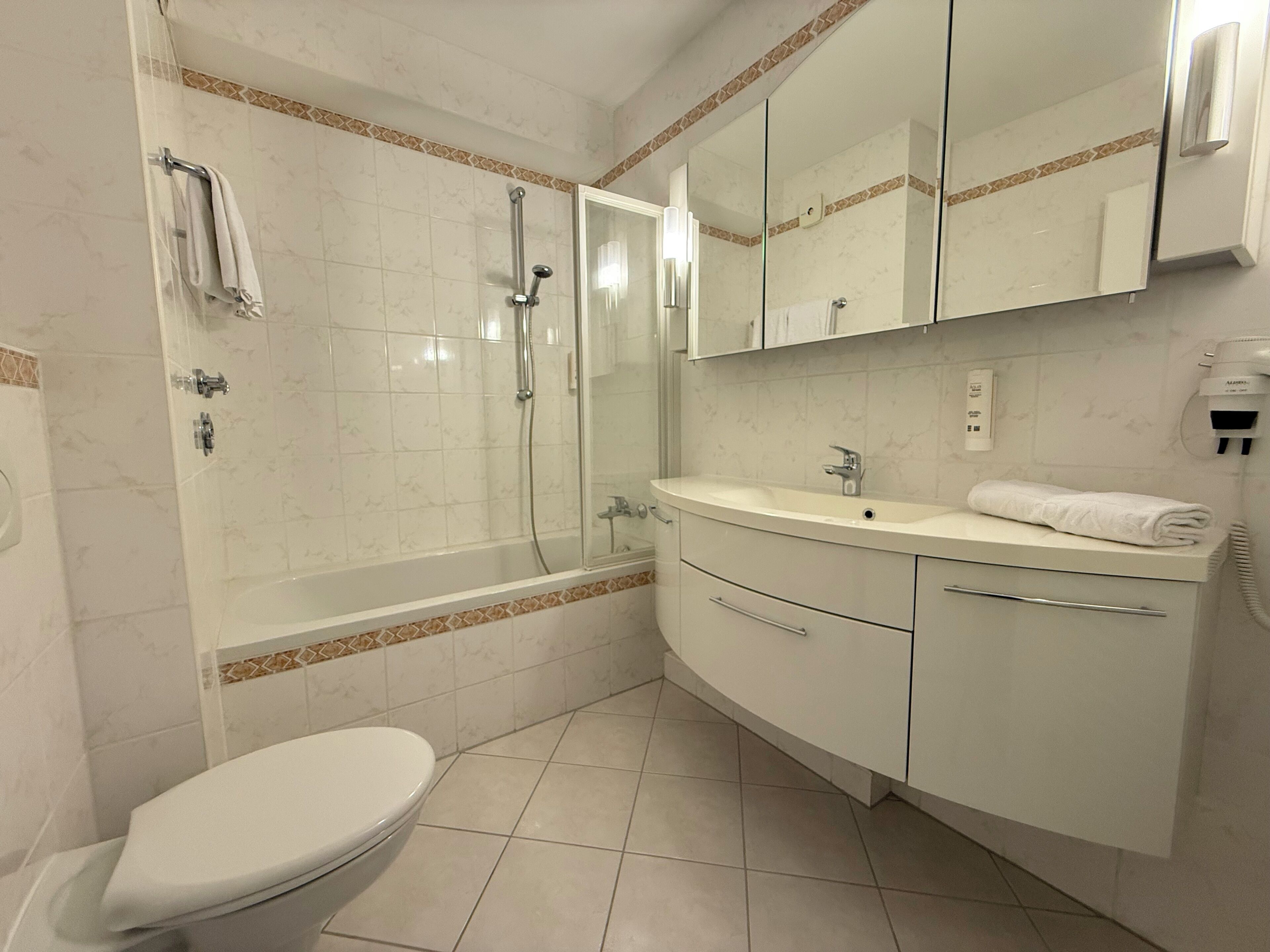 Ein Badezimmer mit Toilette, Dusche, Waschbecken und Spiegel.