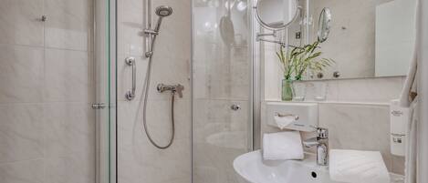 A modern bathroom with a glass-enclosed shower, a white sink, and a mirror.