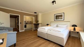 Une chambre d’hôtel équipée d’un lit double, d’un bureau, d’une chaise, d’une kitchenette et d’une salle de bain.