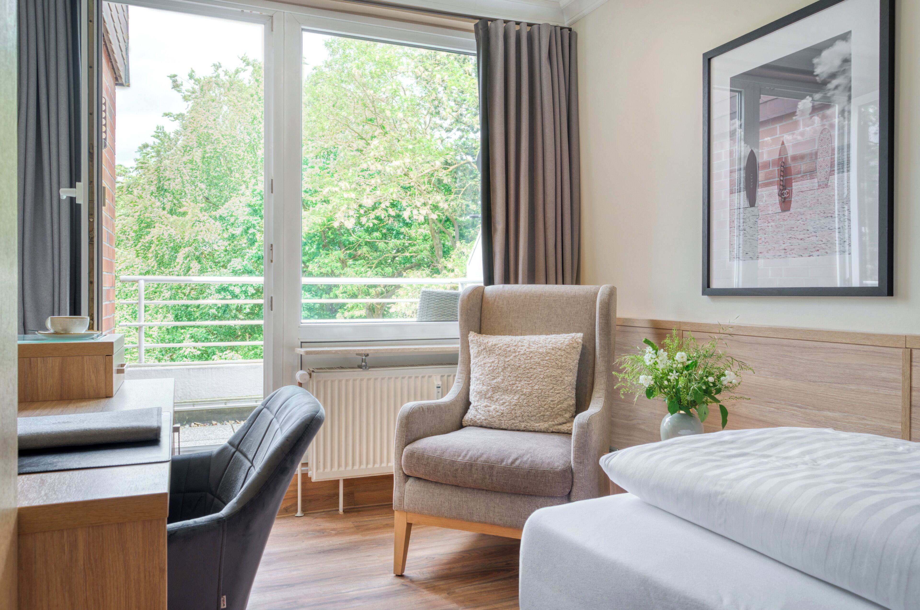 A hotel room with a bed, a chair, a desk, and a window with curtains.