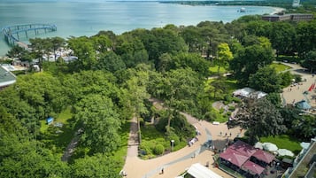 Ein Luftbild eines Parks mit Uferpromenade, einer Brücke und einem Restaurantbereich mit Außenplätzen.