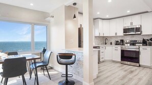 A modern kitchen with white cabinets, stainless steel appliances, and a view of the ocean. - Coastal Retreat Waterfront, Deck, Awesome Views (Wading River)