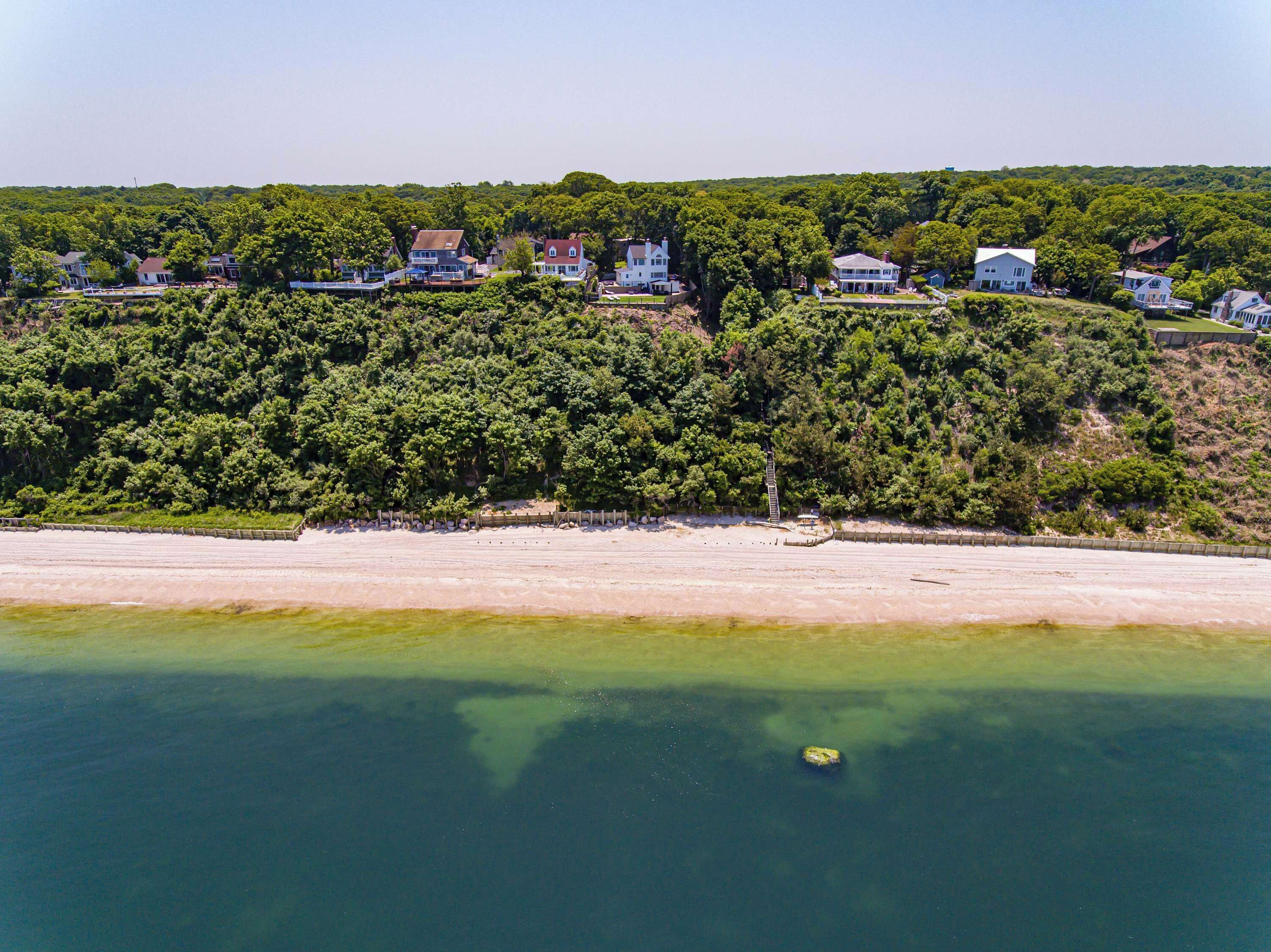 Een kustgebied met huizen op een heuvel en een strand op de voorgrond.