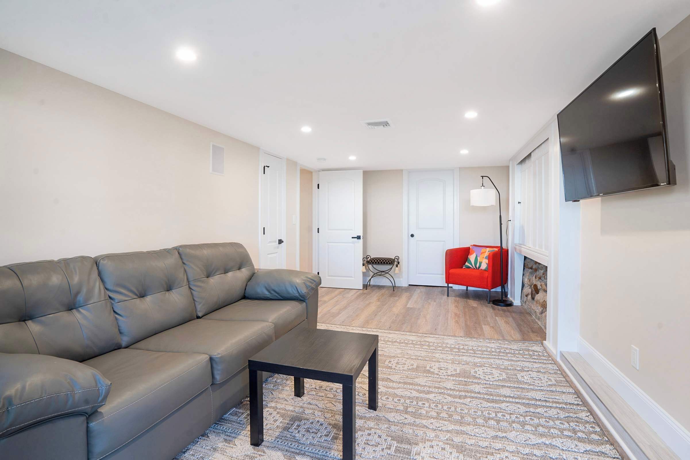 Un salon moderne avec un canapé en cuir, une petite table et un fauteuil rouge.