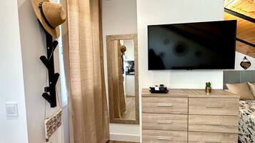 A modern bedroom with a wooden ceiling, a large mirror, a TV, and a wooden dresser.